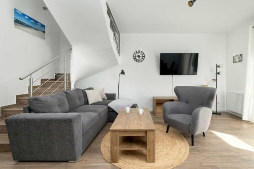 a living room with a couch and two chairs and a table at Spacious House Kołobrzeg with Garden Grill and Parking by Noclegi Renters in Niekanin