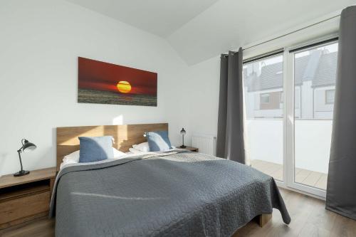 a bedroom with a bed and a large window at Spacious House Kołobrzeg with Garden Grill and Parking by Noclegi Renters in Niekanin