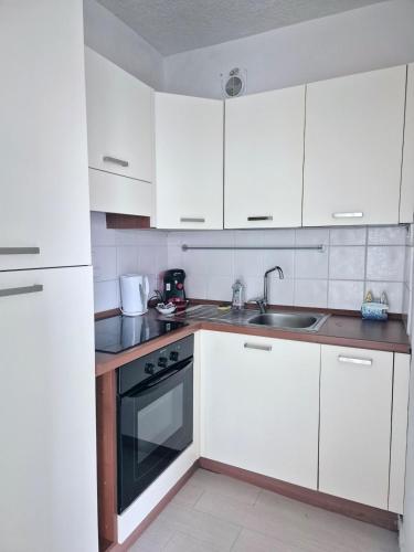 une cuisine avec des armoires blanches et un évier dans l'établissement Studio Les Ligures, à Roquebrune-Cap-Martin