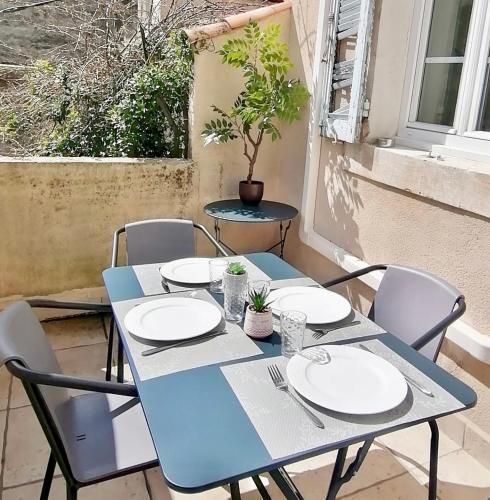 une table bleue avec des assiettes et des chaises blanches sur une terrasse dans l'établissement Appartement 55 m2 avec terrasse, clim, WIFI, Netflix, bureau, à Avignon