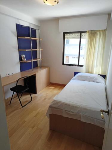 a bedroom with a bed and a desk and a window at Bungalow primera línea de playa in El Campello