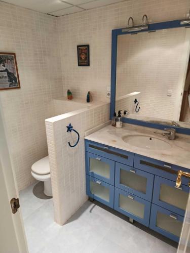 a bathroom with a sink and a mirror and a toilet at Bungalow primera línea de playa in El Campello