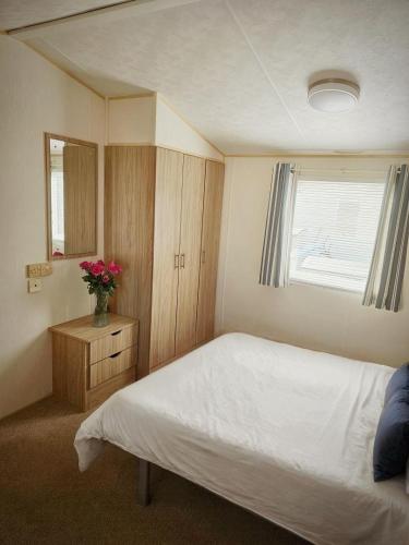 a bedroom with a bed and a vase of flowers at Lyon’s Robin Hood Rhyl caravan sbw in Rhyl