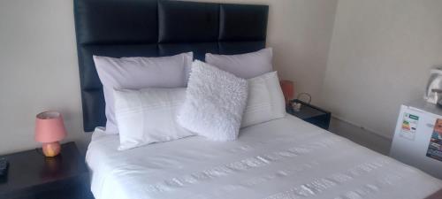 un letto con cuscini bianchi e testiera nera di Princia Guest House a Newcastle