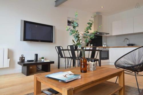 un salon avec une table et une télévision au mur dans l'établissement Luis Mariano Triplex Apartment, à Biarritz