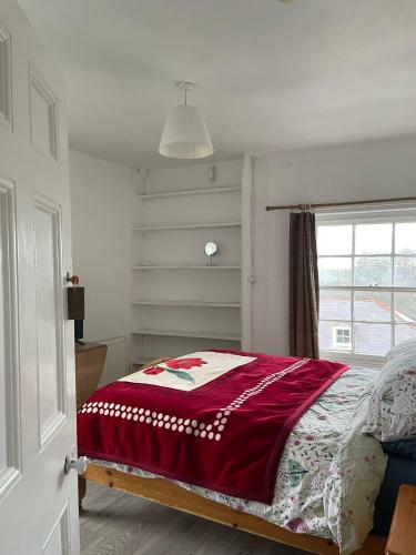 a bedroom with a bed with a red blanket on it at Bryn Awel in Aberystwyth