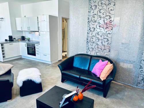 a living room with a black leather couch with a pink pillow at Stylish & central #LoftWerk 2 in Velbert
