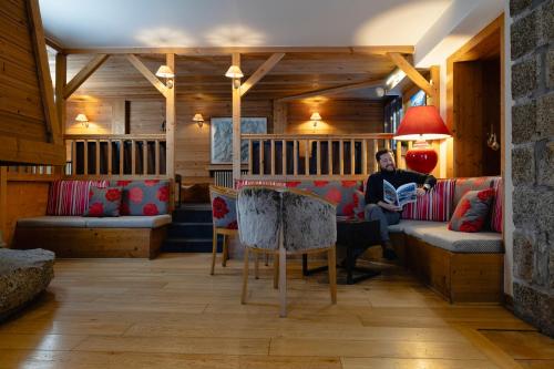 a man sitting on a couch in a living room at Hôtel de L'Arve by HappyCulture in Chamonix-Mont-Blanc