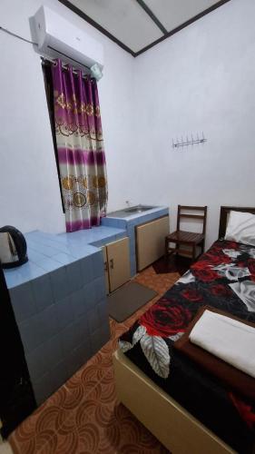 a bedroom with a bed and a desk and a window at Kamar Homestay Soeharni in Jetis