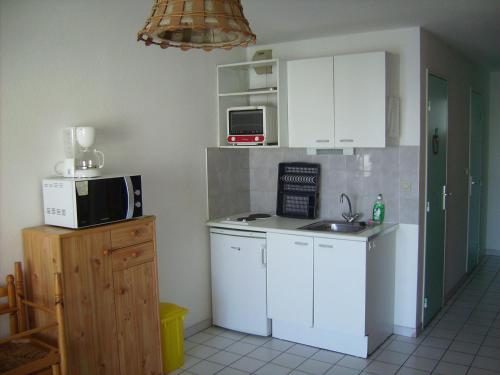 une cuisine avec un évier et un micro-ondes dans l'établissement T2 cabine 35m² + loggia à Sète, parking et vue sur la mer - FR-1-472-120, à Sète