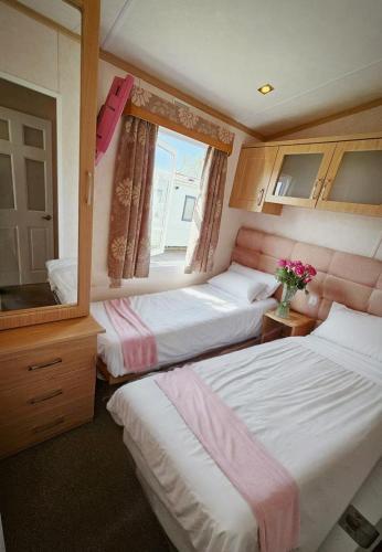 a small bedroom with two beds and a mirror at Luxury lodge lyons robin hood in Rhyl