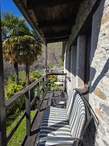 a porch with a bench and a table and a palm tree at Casa Carina - Enchanted rustico in Mergoscia in Mergoscia