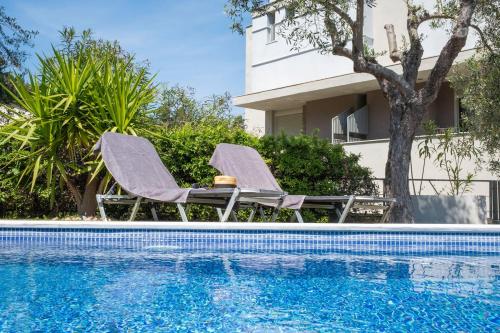 two lounge chairs next to a swimming pool at MD Pool Villa in Chroussos by Halkidiki Villas in Paliouri
