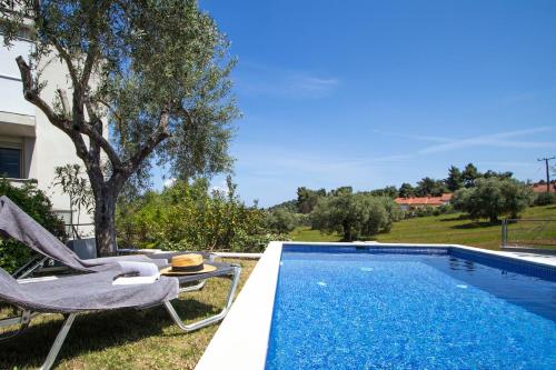 a swimming pool with a chair and a table next to at MD Pool Villa in Chroussos by Halkidiki Villas in Paliouri