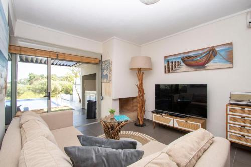 a living room with a couch and a tv at MD Pool Villa in Chroussos by Halkidiki Villas in Paliouri