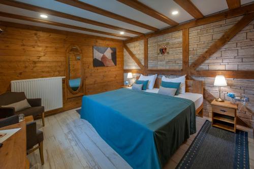 a bedroom with a blue bed in a room with wooden walls at Lakeside Hotel Plitvice in Plitvička Jezera