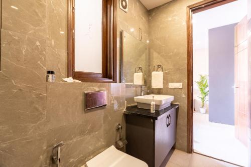 a bathroom with a sink and a toilet and a mirror at Homlee-Anupam 3BHK-Lift-Parking-Saket-Max Hospital in New Delhi