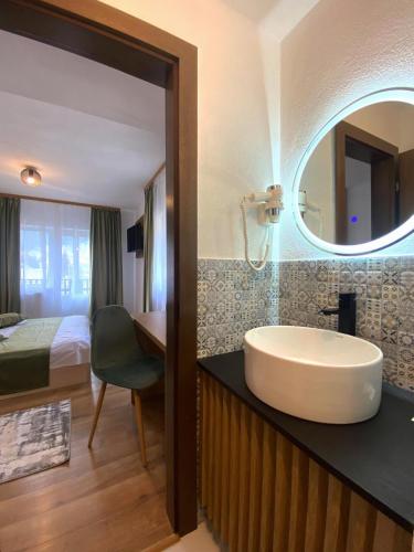a bathroom with a sink and a bed and a mirror at Regina Munților Spa&Confort in Moieciu de Sus