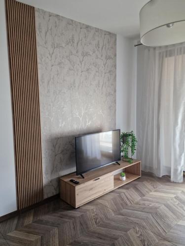 a living room with a flat screen tv on a wooden stand at Apartament Jagiełły Park Olsztynek in Olsztynek