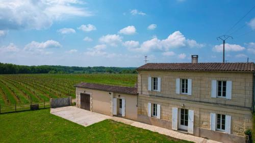 a building in front of a field of vines at Maison au coeur des vignes in Puisseguin
