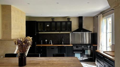 une cuisine avec des armoires noires et une table en bois dans l'établissement Maison au coeur des vignes, à Puisseguin