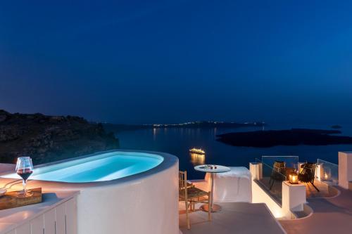a swimming pool at night with a view of the water at Cocoon Suites in Imerovigli