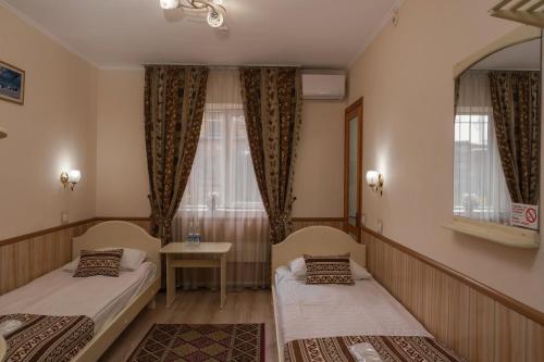 a room with two beds and a table and windows at Alpinist Hotel in Bishkek