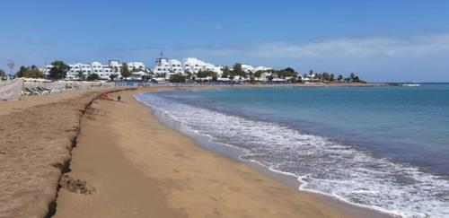 a beach with people walking on the sand and the water at Sunset&Suite Puerto del Carmen in Tías