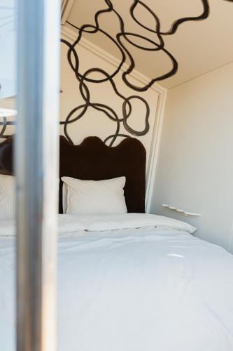a bedroom with a white bed with a black headboard at DE BUITENKANS urban camping - unique cabins in Rotterdam