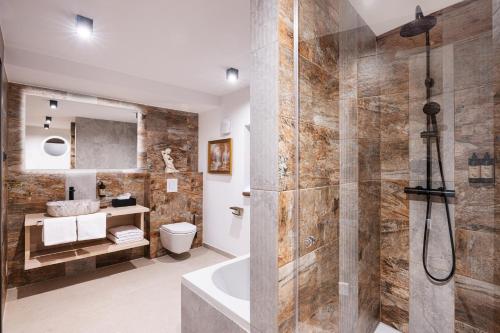 a bathroom with a shower and a tub and a toilet at Hotel Julian Alps in Zgornje Gorje