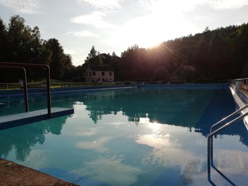 a swimming pool with the sun reflecting in the water at Seßles Waldhäusschen Dietzhausen in Suhl