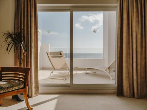 a room with a sliding glass door with a chair at Ibara Ibiza Hotel Boutique in Es Cana