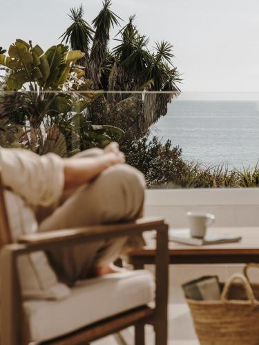 a person sitting on a chair looking out at the ocean at Ibara Ibiza Hotel Boutique in Es Cana