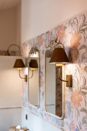 une salle de bain avec deux miroirs sur un mur dans l'établissement Le Prieuré - Château La Martinette, au Thoronet