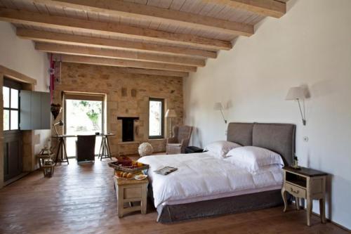 een slaapkamer met een groot wit bed en een houten vloer bij Villa Athermigo in Gavalochori