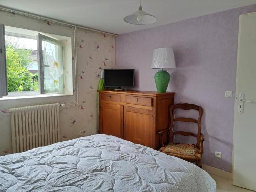 - une chambre avec un lit, une télévision et une chaise dans l'établissement Au doux refuge, à Malemort-sur-Corrèze