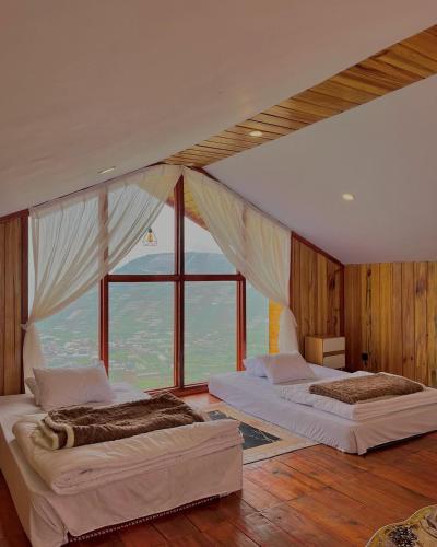 two beds in a room with a large window at Tower Hill Cabin Dieng in Diyeng