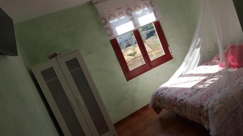 a small bedroom with a bed and a window at Hostal A La Sombra Del Laurel in Navarrete
