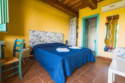 a bedroom with a blue bed and yellow walls at Borgo De Salaioli in Scansano