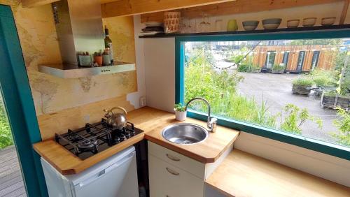 a small kitchen with a sink and a window at DE BUITENKANS urban camping - unique cabins in Rotterdam