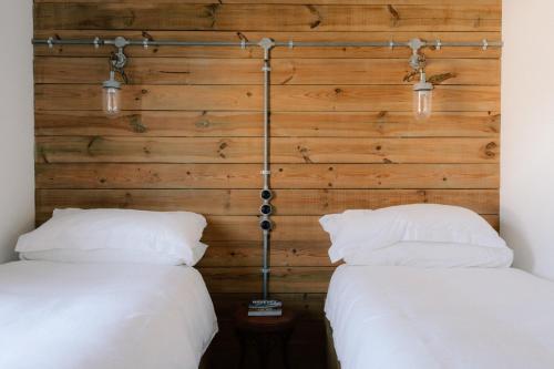 two beds in a room with wooden walls at Cabin at Mackay's in Durness