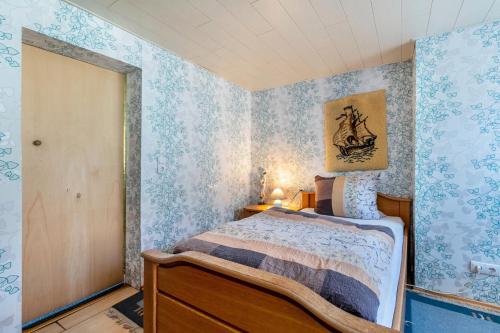 a bedroom with a bed with blue wallpaper at Lüddes Fischerhuus in Husum