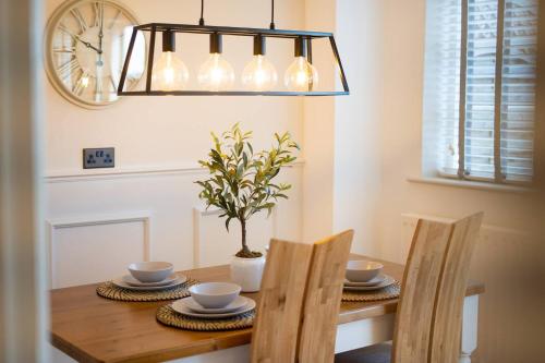 a dining room table with two chairs and a chandelier at Stylish 2 Bedroom Cottage with Hot Tub and Parking in Bewdley