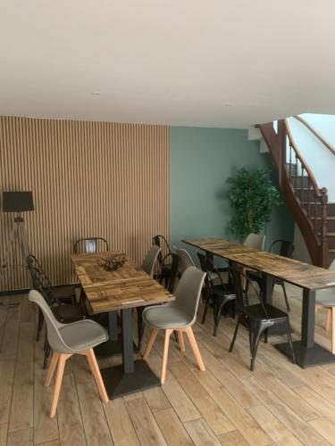un restaurant avec des tables et des chaises en bois et un escalier dans l'établissement Little America - Appart Hôtel 3km Futuroscope, à Jaunay-Clan