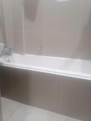 El baño incluye bañera blanca con lavamanos. en Pearl Holiday homes, en Vosburg
