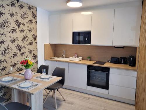 a kitchen with white cabinets and a table with chairs at Aura Residence Apartman in Sárvár