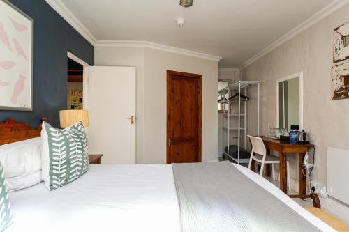 a bedroom with a large bed and a desk at Adventure Pad's by The Farmhouse Hotel in Langebaan