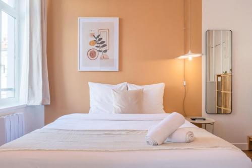 une chambre avec un lit avec des draps blancs et un miroir dans l'établissement Charming Lille St Michel studio, à Lille