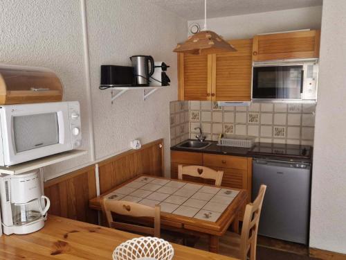 une petite cuisine avec une table et un micro-ondes dans l'établissement Studio 3 pers. 2* avec balcon exposé Ouest, centre Valloire, parking privé, animaux acceptés - FR-1-263-491, à Valloire