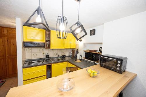 a kitchen with yellow cabinets and a wooden counter top at Maison Citron - Explore Courmayeur Mont Blanc in Villair